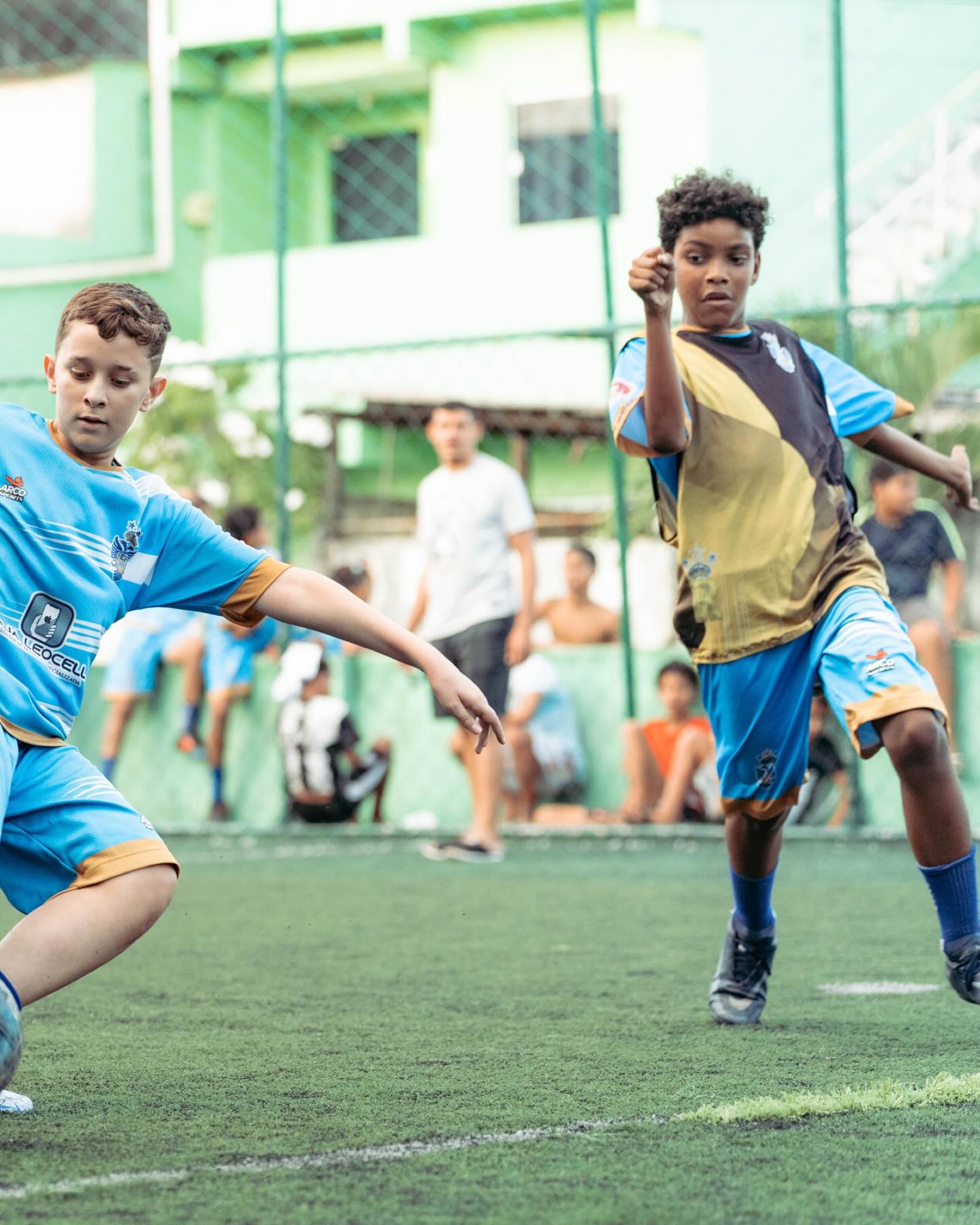 Atletas mirins disputando a bola em campo society